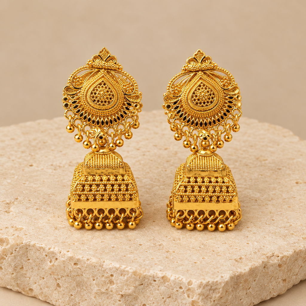 Gold-tone jhumka earrings pair on a cream stone display
